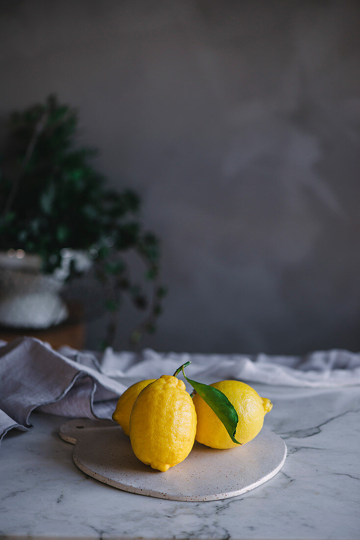 Drei frische Zitronen auf Küchenbrett