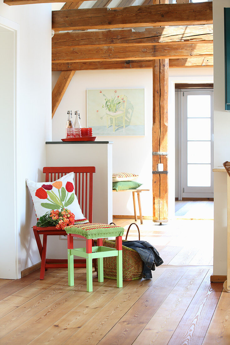 Hand-sewn scatter cushions on red chair and stool with crocheted cover