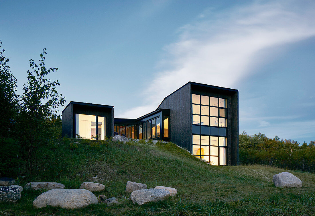 Kubisches Architektenhaus am Abend mit beleuchteten Glasfronten