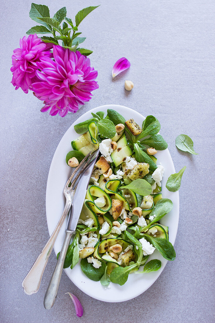 Salad with songino, goat cheese, zucchini and hazelnuts