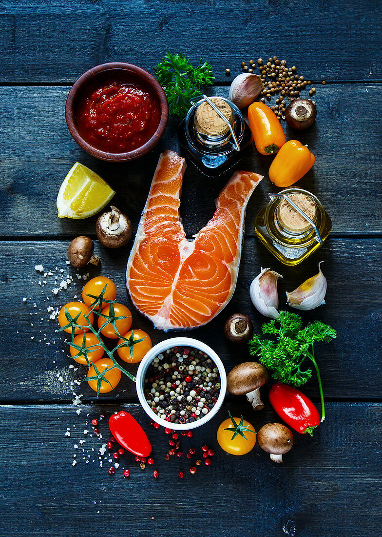 Raw steak of salmon with fresh ingredients for tasty cooking on rustic wooden background