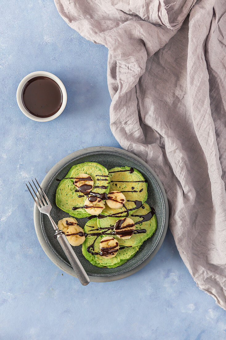 Green pancakes with banana and chocolate sauce