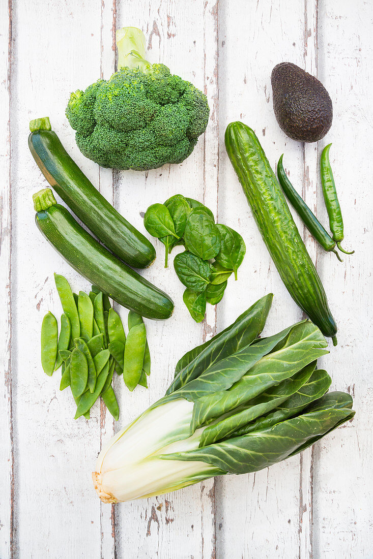 Grünes Stillleben mit Brokkoli, Avocado, Zuckererbsen, Mangold, Zucchini, Gurke, Babyspinat und grünen Chilischoten