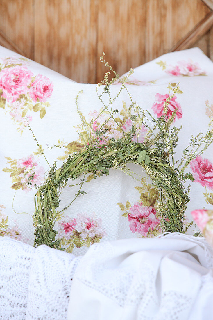 A scented herbal wreath on a pillow with a rose motif