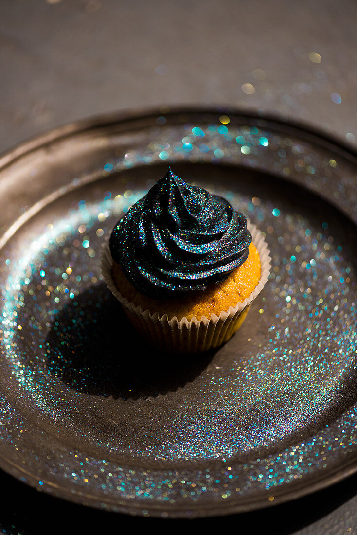 A cupcake with black buttercream and glitter