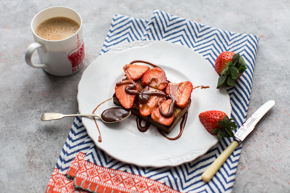 Roggenbrotscheibe belegt mit Erdbeeren und beträufelt mit Schokosauce