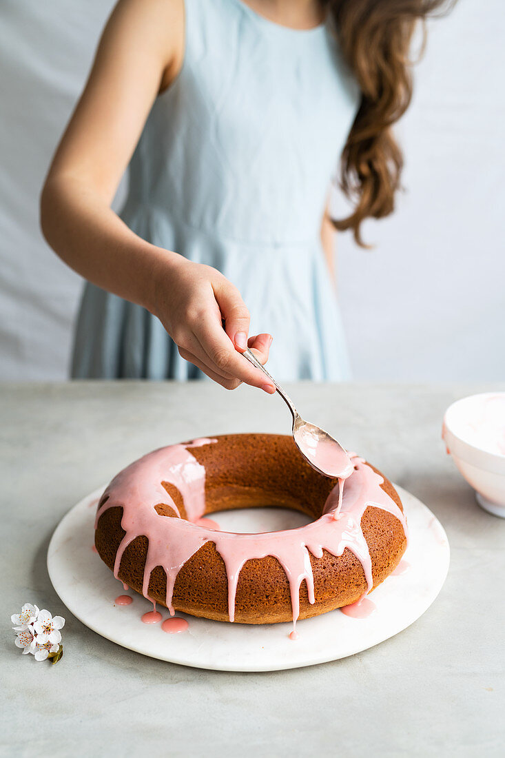 Einen Napfkuchen mit rosa Zuckerglasur glasieren