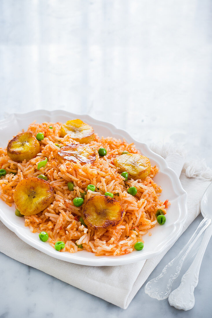 A plate with traditional mexican red rice (arroz rojo) with peas and fried plantains