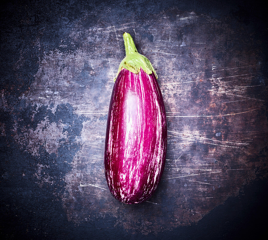 An eggplant on a dark metal background (top view)