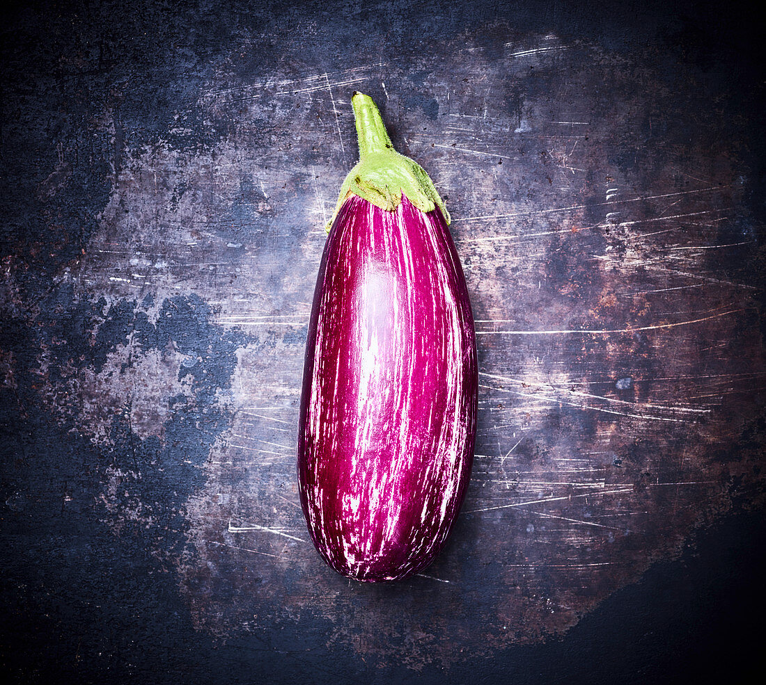 Eine Aubergine auf dunklem Metalluntergrund (Aufsicht)