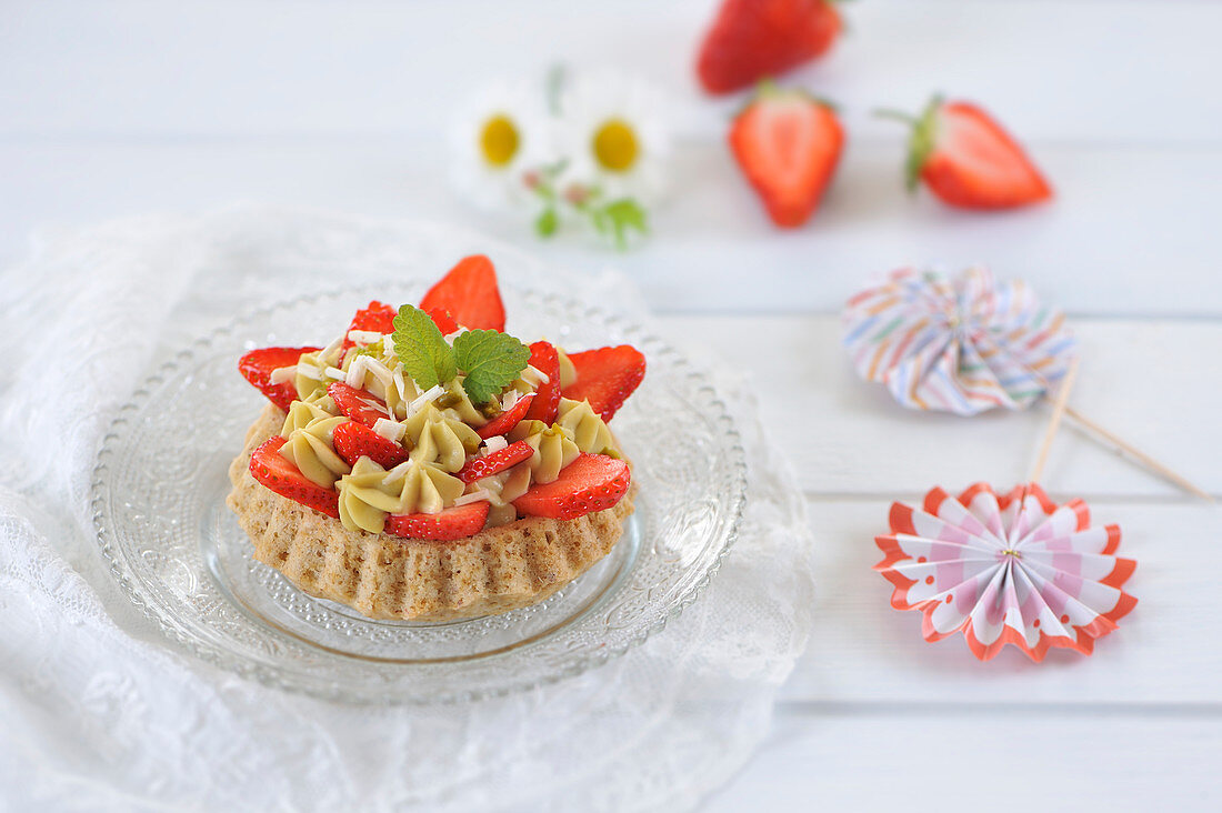 Vegane Erdbeertörtchen mit Mandelbiskuit und Pistaziencreme, dekoriert mit frischen Erdbeeren und weisser Schokolade