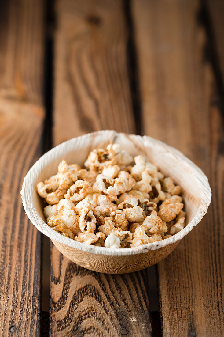 Gilded popcorn in a bowl on a wooden surface