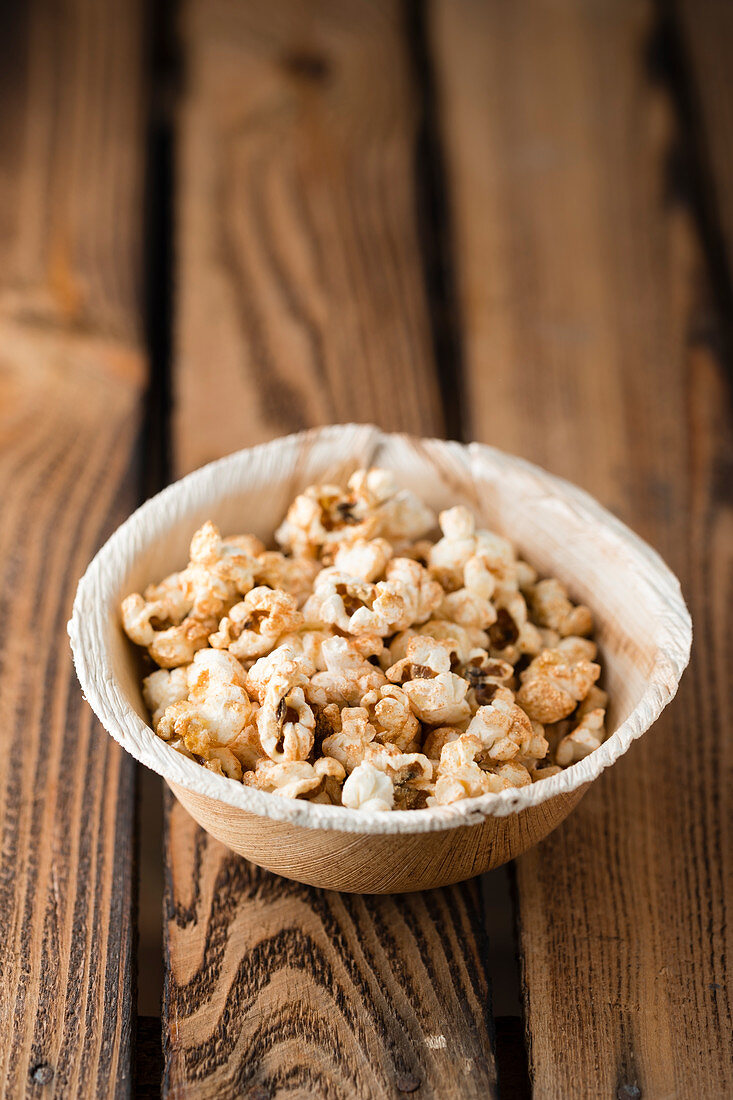 Vergoldetes Popcorn in Schälchen auf Holzuntergrund