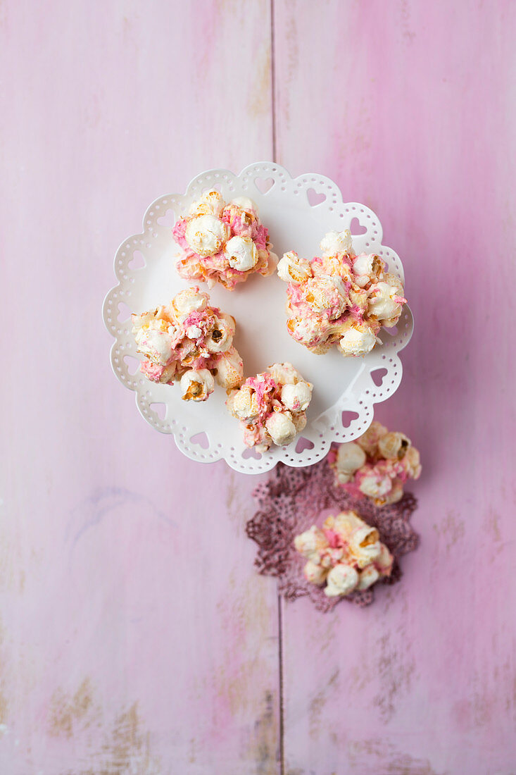 Marshmallow-Popcorn-Bällchen vor pinkfarbenem Hintergrund (Aufsicht)