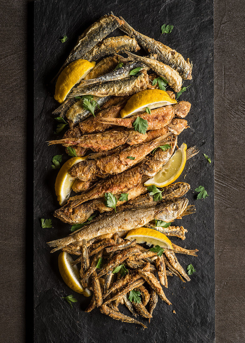 Verschiedene frittierte Fische mit Zitronenspalten und Petersilie