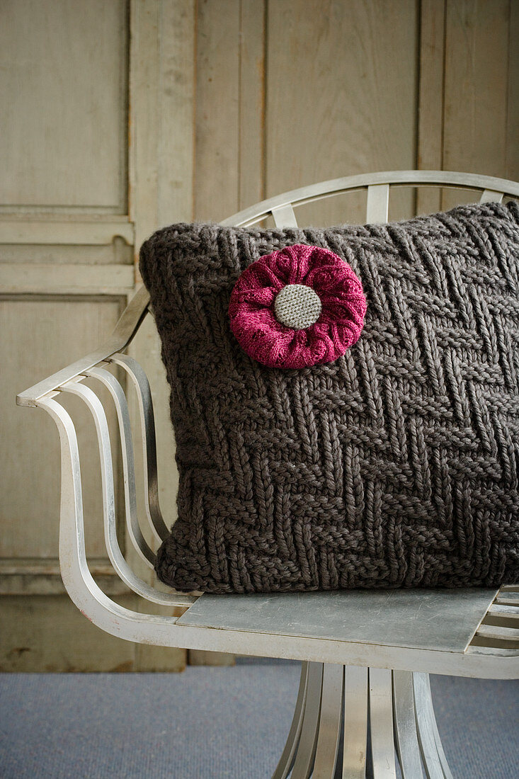 Cushion with knitted cover and knitted flower on chair