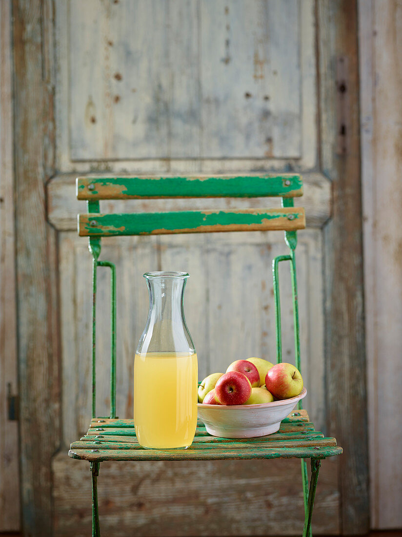 Apfelsaft und Äpfel auf Gartenstuhl