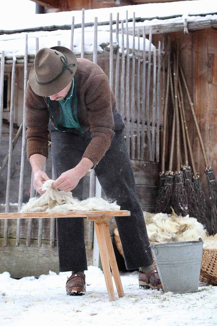 Mann bearbeitet frisch geschorene Schafwolle