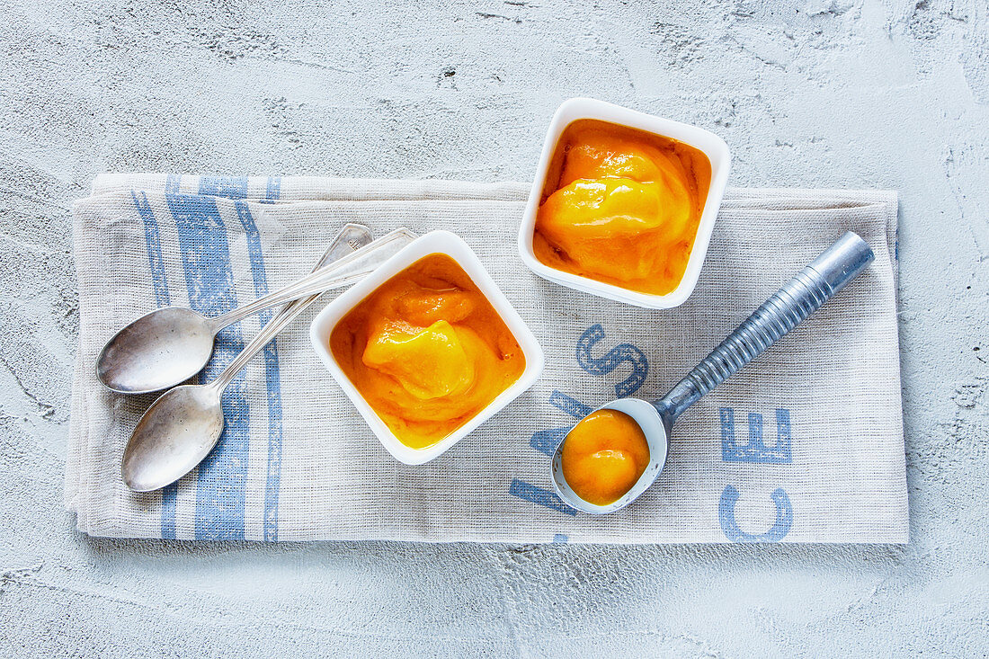 Mango sorbet in a bowl with an ice cream scoop