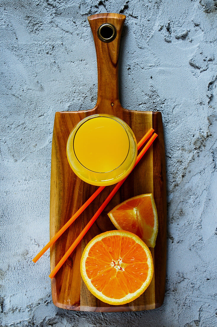 Frisch gepresster Orangensaft in Glas auf Holzbrett