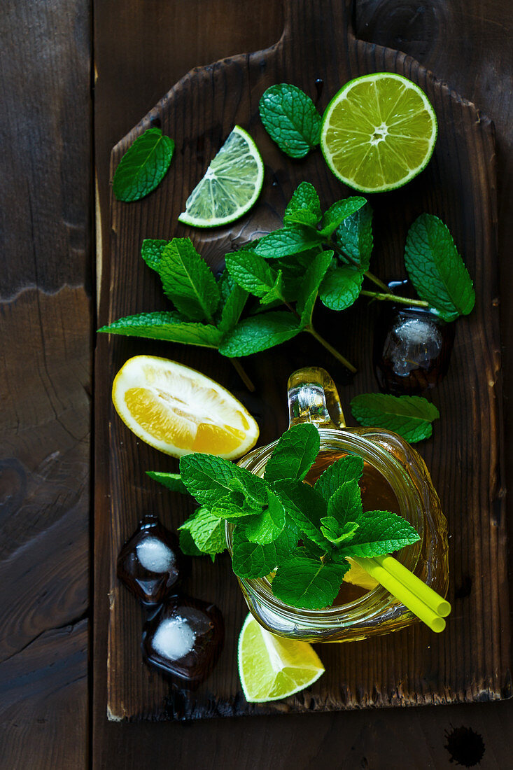 Green tea with lime, lemon and mint in a glass jug on a wooden board