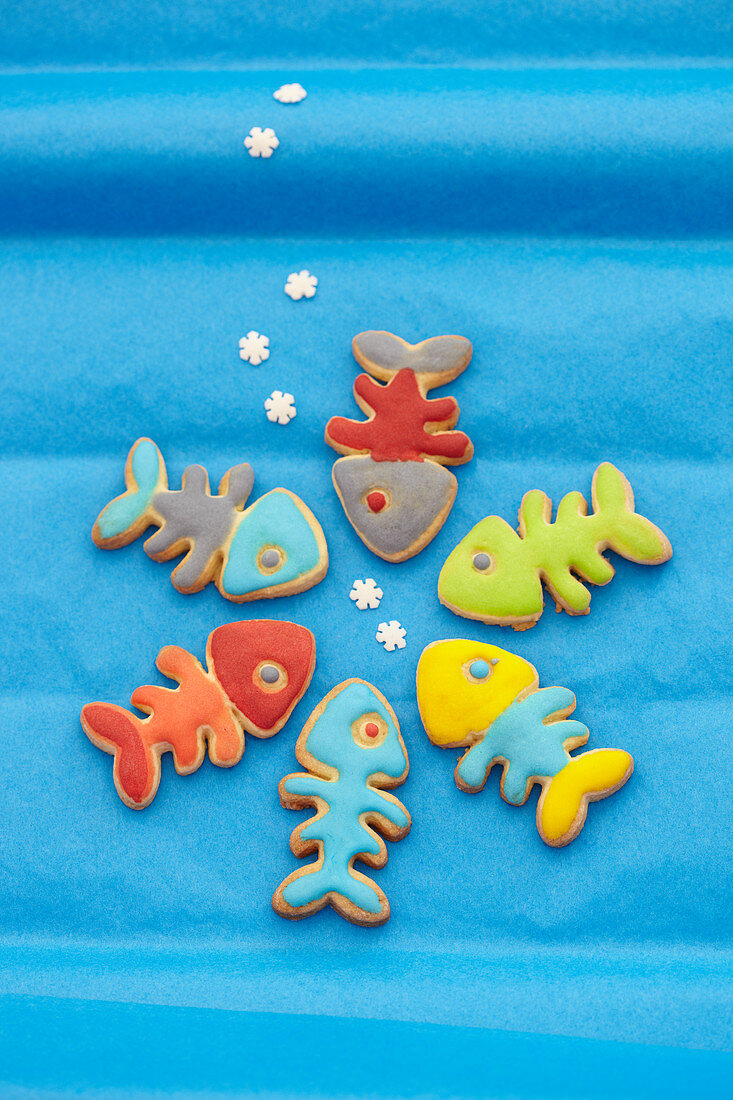 Kekse in Fischform mit bunter Zuckerglasur auf blauem Untergrund