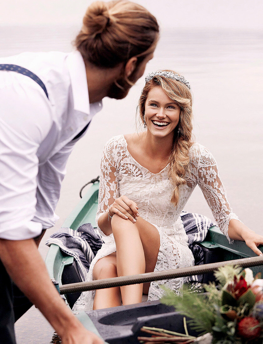 A young woman wearing a white wedding dress sitting in a boat