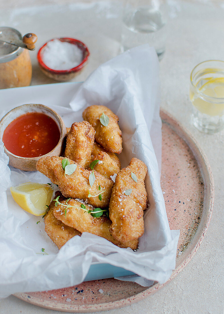 Breaded chicken strips with salt, thyme, lemon and a dip