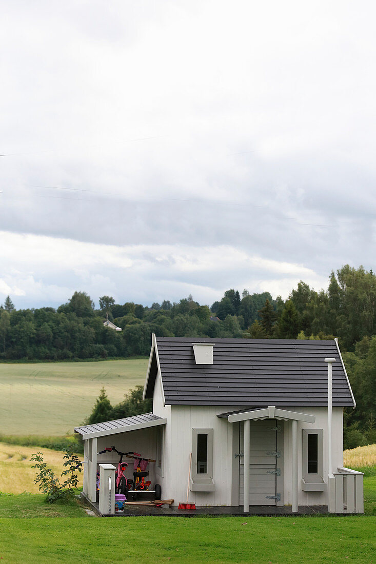 Kinderspielhaus im Garten vor weiter Landschaft