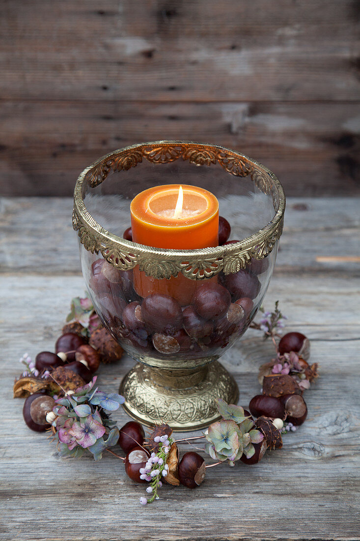 Candle and horse chestnuts in glass goblet and wreath handmade from horse chestnuts