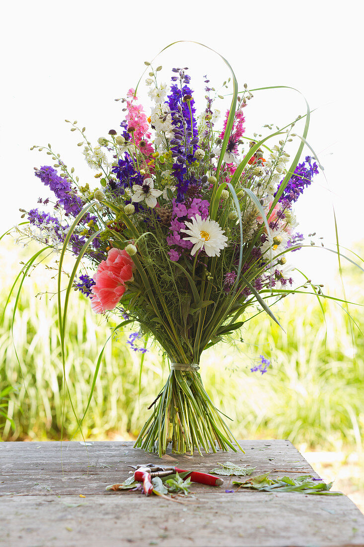 Summer bouquet with delphiniums on garden table