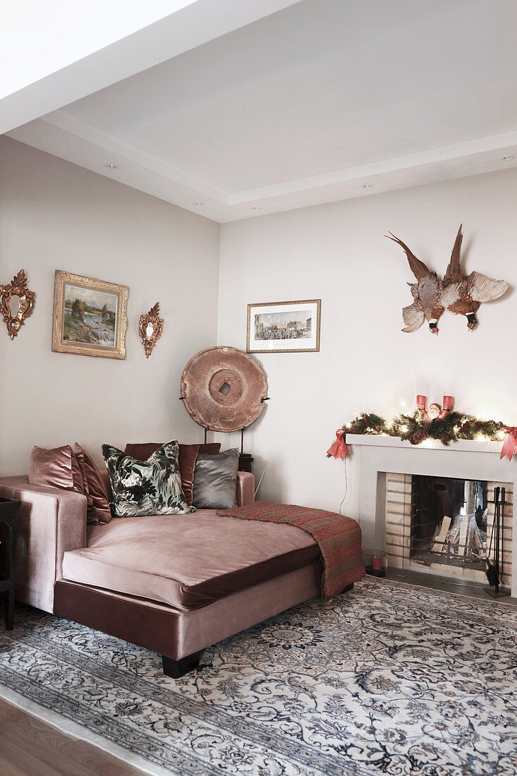 Dusky-pink velvet couch next to open fireplace in living room