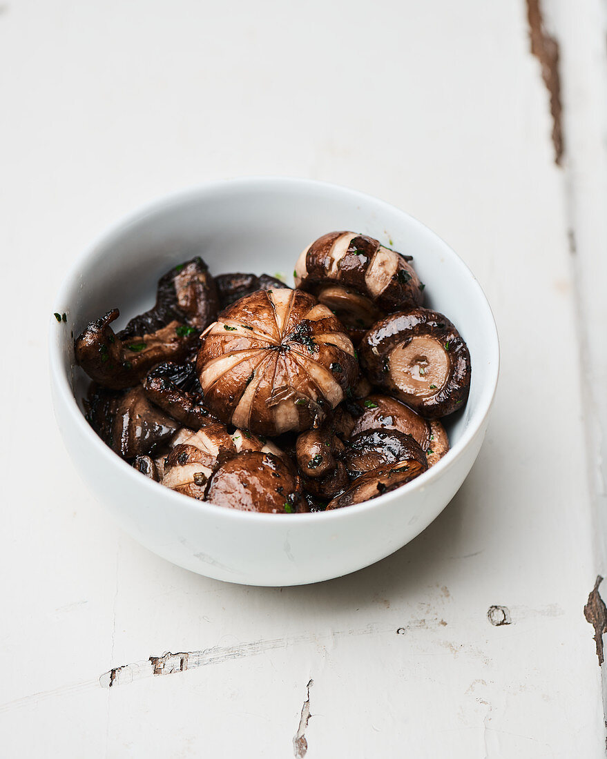 Pan-fried dark champignons in a bowl, garnished with parsley