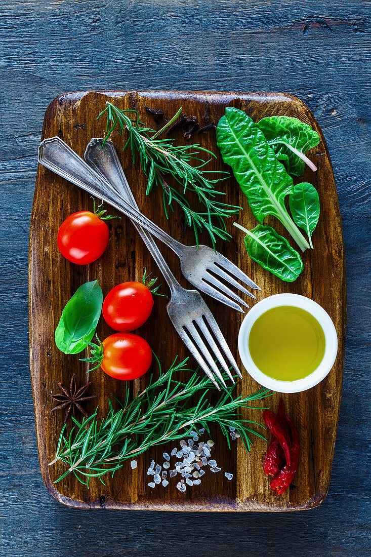 Vintage wooden chopping cutting board and fresh ingredients for healthy cooking on dark rustic background