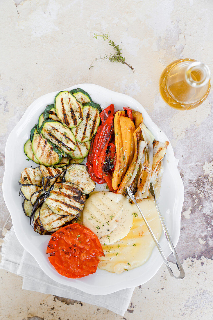 Dish with grilled vegetables, courgettes, aubergines, peppers, tomatoes, spring onions, and scamorza