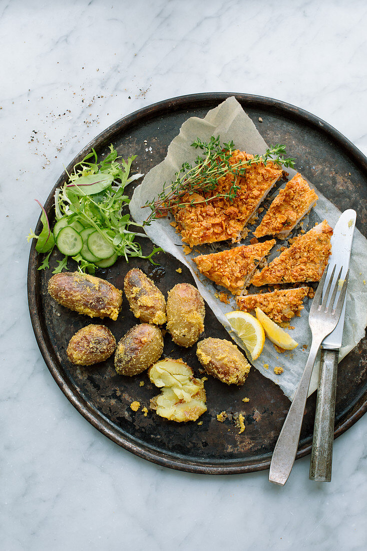 Hähnchenschnitzel mit Cornflakes-Kruste, Polentakartoffeln und Salatgarnitur auf rundem Blech