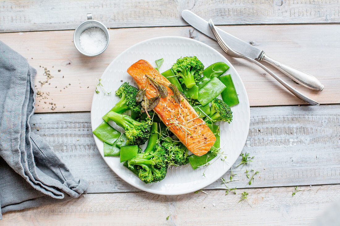 Salmon on a bed of green vegetables with mange tout