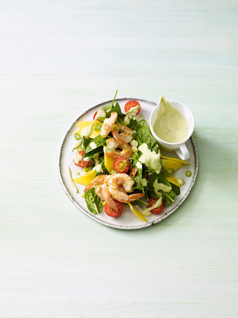 Spinach salad with fried prawns and avocado dressing