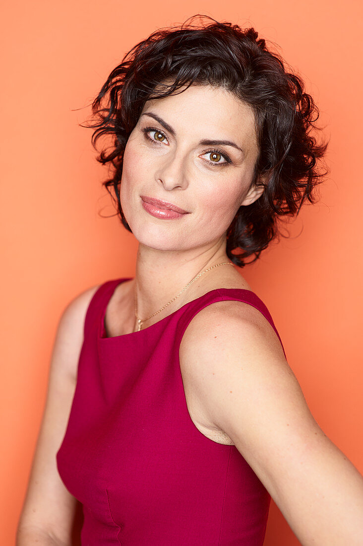 A dark haired woman wearing a red cocktail dress