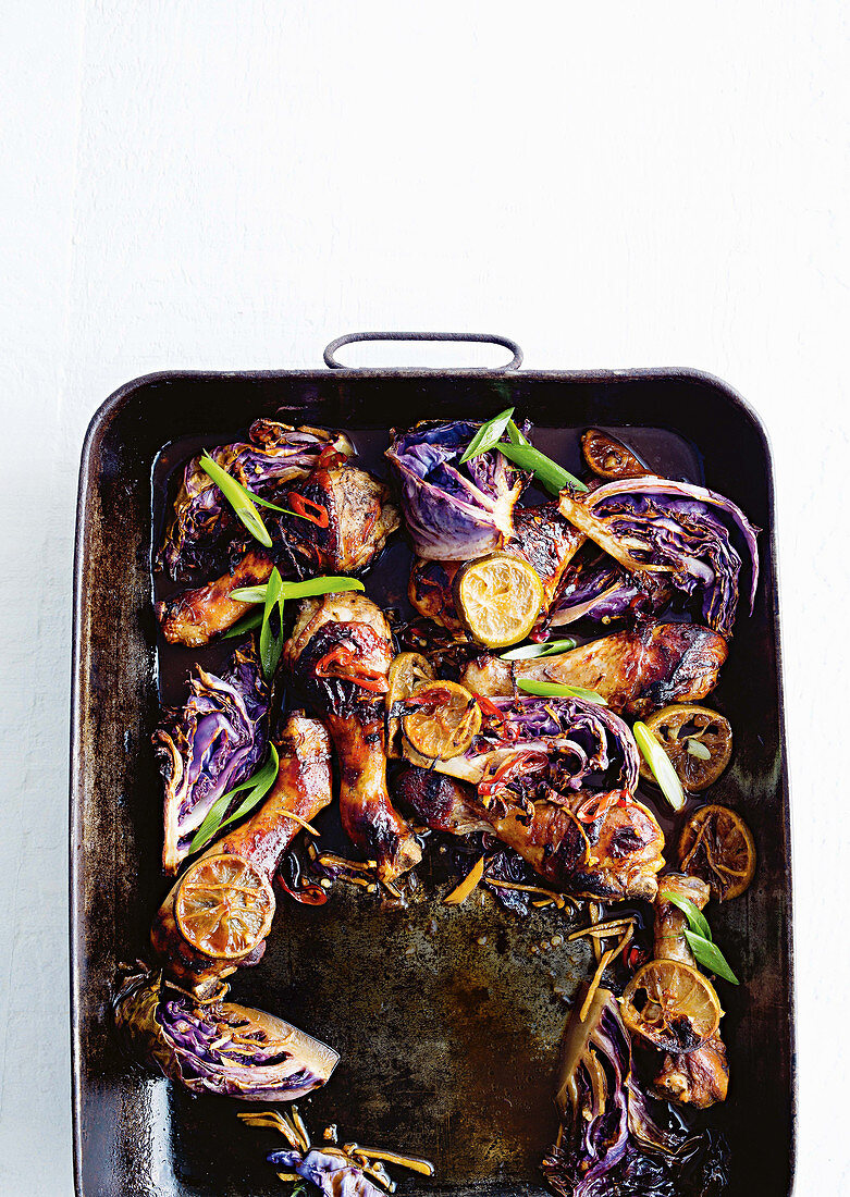 Spicy chicken legs with lime and red cabbage in a roasting dish