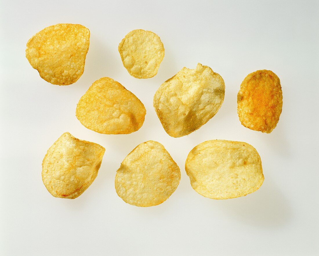 Acht einzelne Kartoffelchips vor weißem Hintergrund