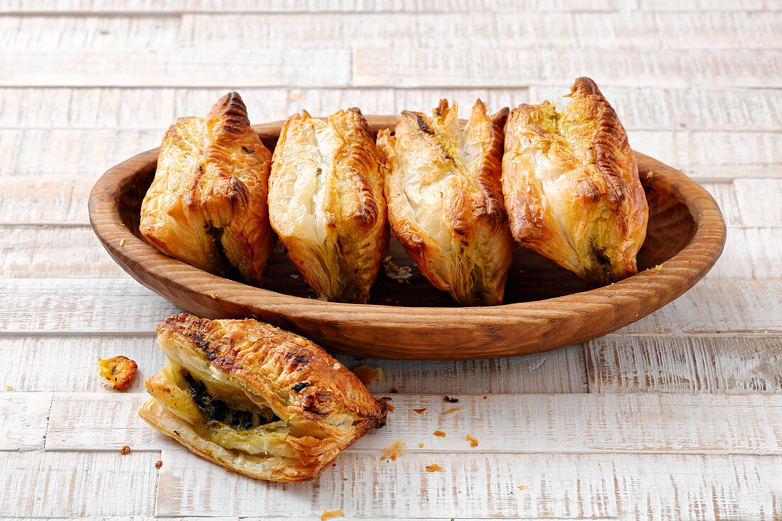Stuffed spinach pastries in a wooden bowl