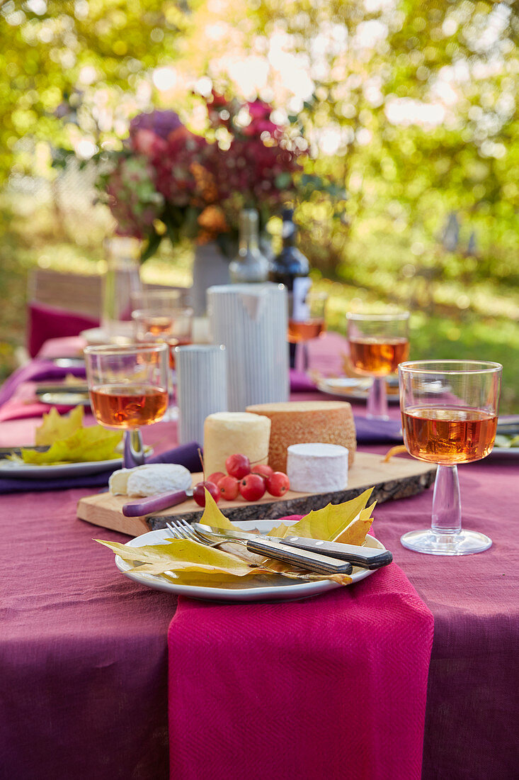 A cheese platter on a festively laid table in an autumnal garden