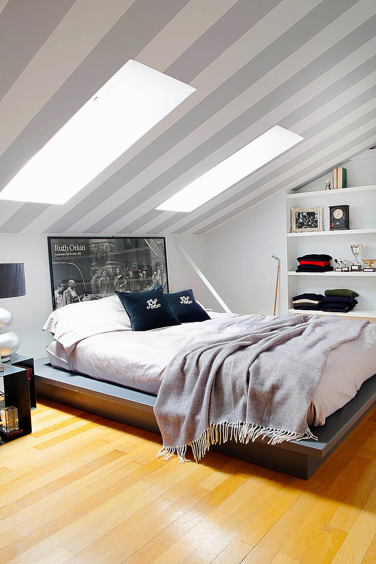 Doppelbett im Dachzimmer, grau-weiß gestreifte Tapete an der Decke