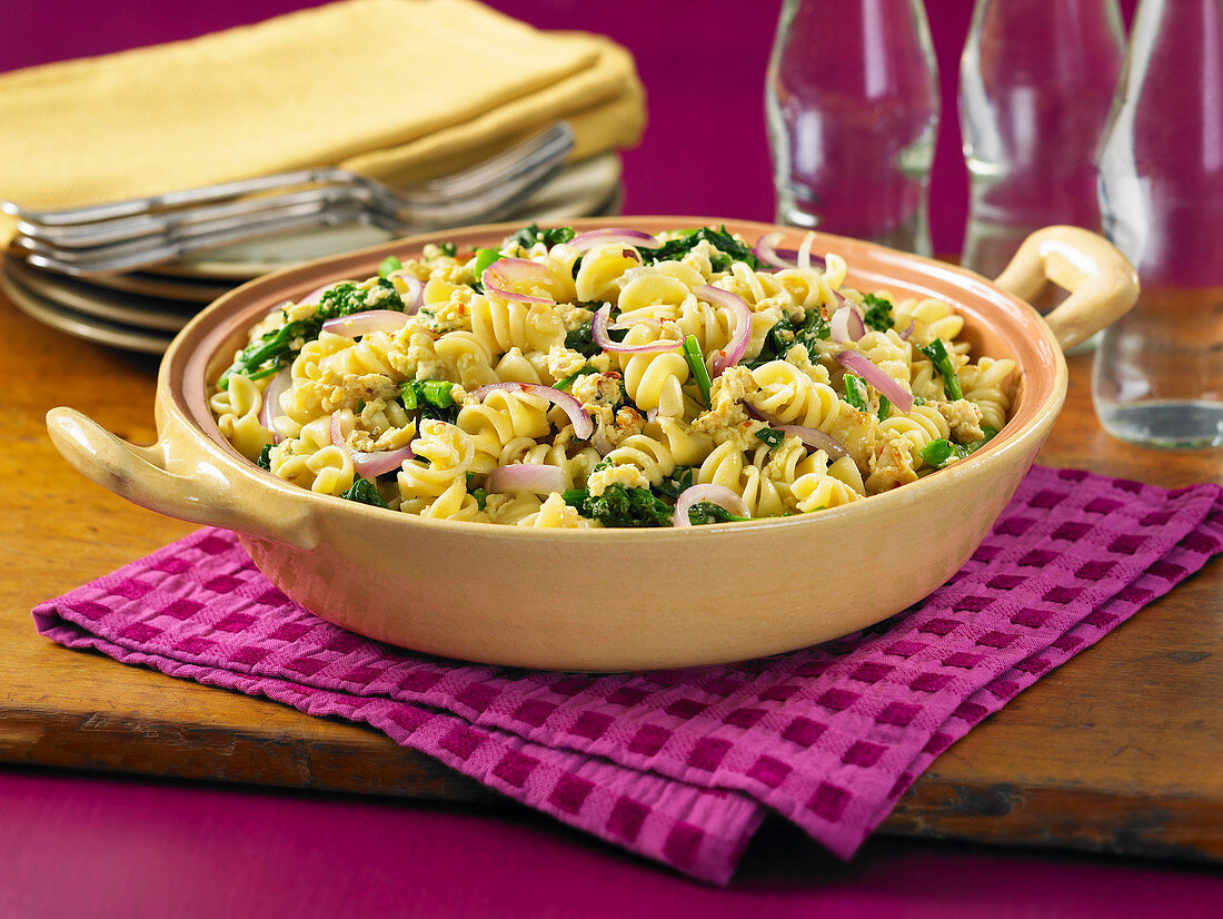 Rotini with broccoli and red onions in a baking dish