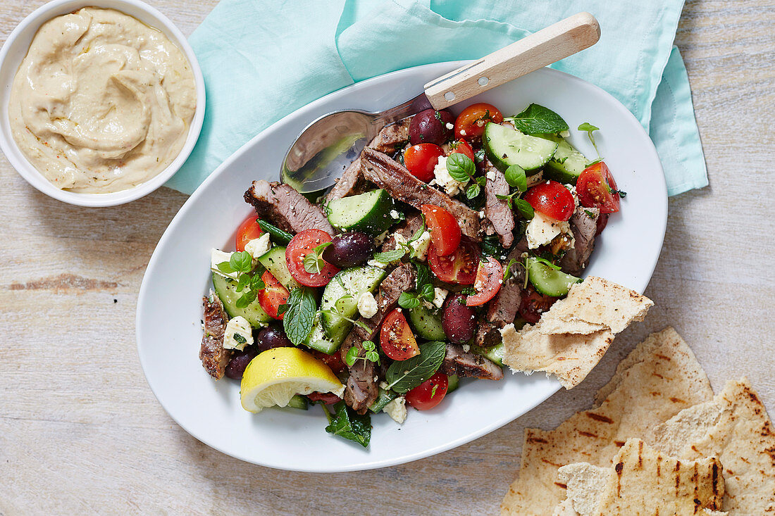 Griechischer Salat mit Lammflleisch serviert mit Dip und Fladenbrot