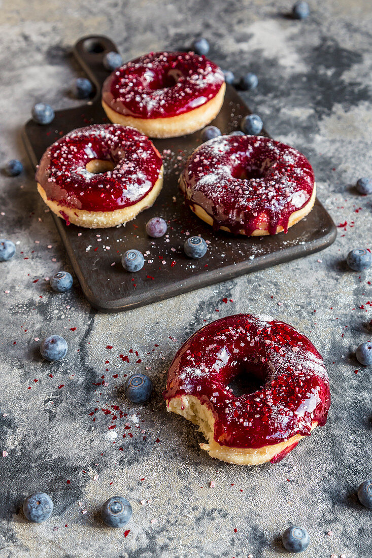 Donuts mit Blaubeerglasur und Glitzerpulver