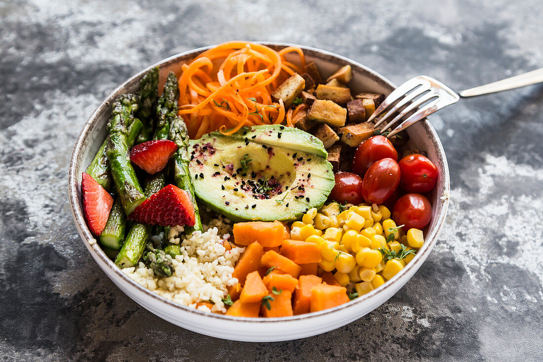 Buddha Bowl mit Bulgur, grünem Spargel, Erdbeeren, Karotten, Tofu, Tomaten, Mais, Süßkartoffeln und Avocado