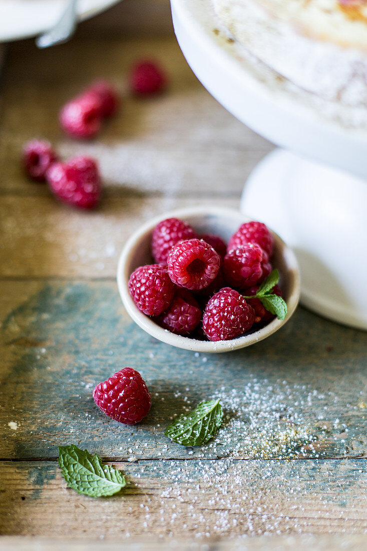 Schälchen mit Himbeeren und Minze auf rustikaler Holzoberfläche