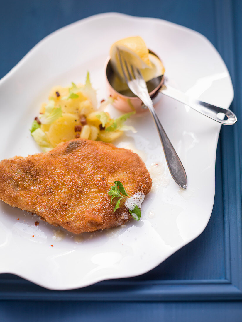 Breaded pork chop with endive and potato salad